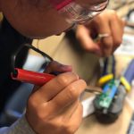 PCC marine science student solders wires on a circuit board.